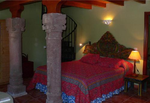 Zalamea la RealCortijo Zalamea的一间卧室配有一张带红色被子和两柱床的卧室