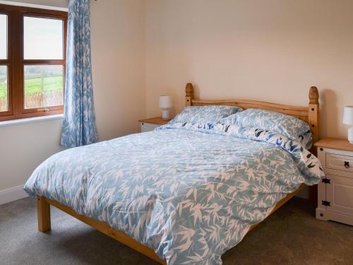 EdlinghamQuails Nest的一间卧室配有一张带蓝色棉被的床和窗户。
