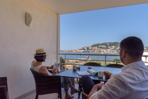 阿雅克修阿加西奥阿米劳特酒店的两人坐在桌子上,享有海景