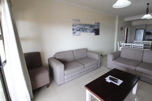 乌旺戈海滩Saints View Resort Unit 21的客厅配有两把椅子、一张沙发和一张桌子