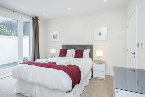 SurbitonRoomspace Serviced Apartments - Lockwood House的白色卧室配有一张带红色枕头的大床