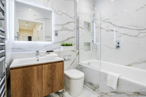 SurbitonRoomspace Serviced Apartments - Lockwood House的浴室配有盥洗盆、卫生间和浴缸。