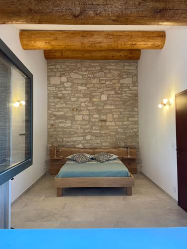 塞雷斯特Les Néfliers Gîte的一间卧室设有一张床和砖墙