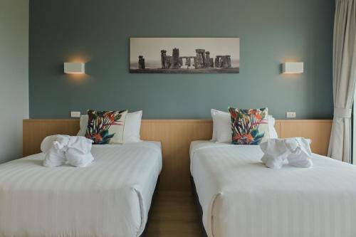 拉差汶里Le Lert Hotel Ratchaburi的配有白色床单的酒店客房内的两张床