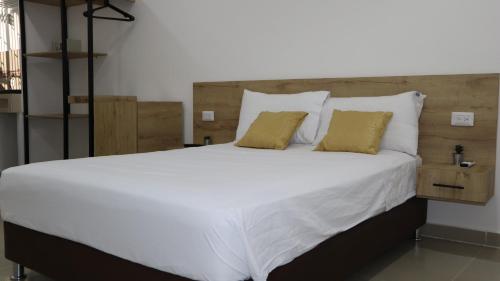 里奥阿查D'Rio Aparta estudios的一张配有白色床单和黄色枕头的大床