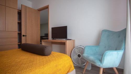 乌鲁阿潘Shanarani Apartament的一间卧室配有一张床、一把椅子和电视