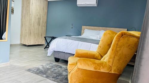 弗里尼欣Khanyisa Lifestyle的一间卧室配有一张床和一张黄色椅子