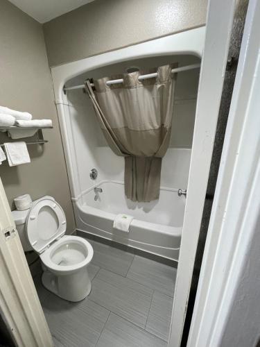 孟菲斯速7汽车旅馆的浴室设有卫生间和带窗帘的浴缸。