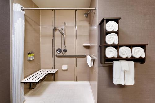 比林斯比林斯智选假日酒店及套房的带淋浴、长凳和毛巾的浴室