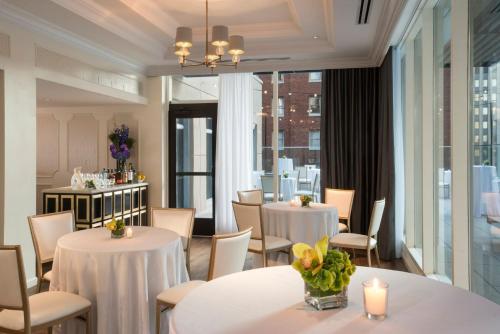 匹兹堡摩纳哥匹兹堡金普顿酒店的餐厅设有白色的桌椅和窗户。