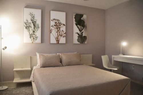 萨拉索塔Clematis House near Arlington Park with Heated Pool的一间卧室配有一张床,墙上有三幅画作