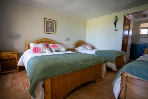 Las CabrasHotel Jardin del Lago的一间卧室配有两张带绿床单和粉红色枕头的床。