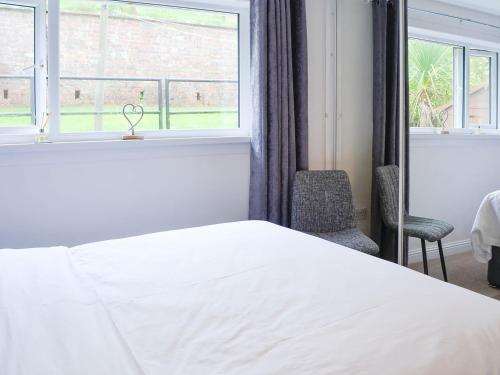 波特帕特里克Thistle Cottage的卧室配有白色的床和窗户。