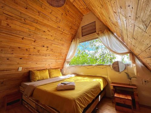 大叻Nấp ở TEEPEE homestay的木制客房的一间卧室配有一张床,设有窗户