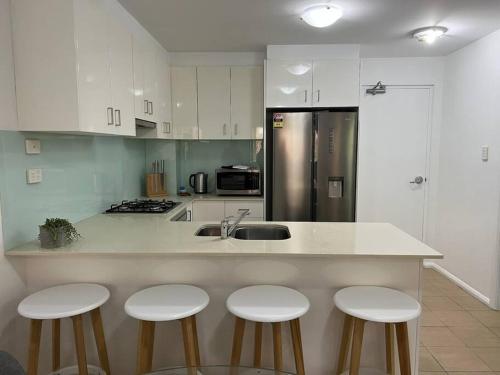 凯阿玛2 bedroom modern coastal retreat的厨房配有白色橱柜和带四把凳子的台面