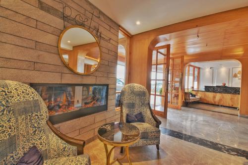 西姆拉雪松Spa大酒店的客厅配有两把椅子和壁炉