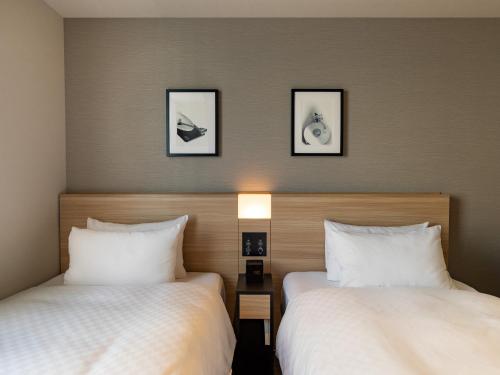 东京东京秋叶原菲诺贝斯特韦斯特酒店的酒店客房,设有两张床和两张墙上的照片