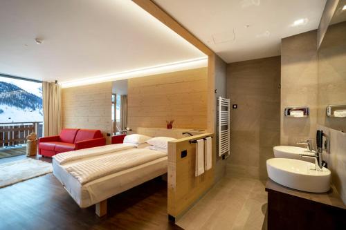 利维尼奥Alpen Resort Bivio的一间卧室配有一张床,浴室设有水槽