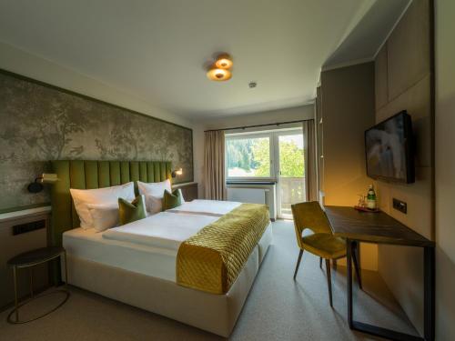 沃格尔Hotel Hennersberg的一间卧室配有一张床、一张书桌和一个窗户。