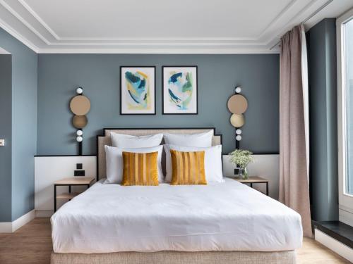 柏林numa I Arc Rooms & Apartments的卧室拥有蓝色的墙壁,配有一张带黄色枕头的白色床。