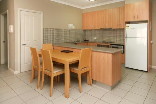 格里菲斯Centrepoint Apartments Griffith的厨房配有木桌和白色冰箱。
