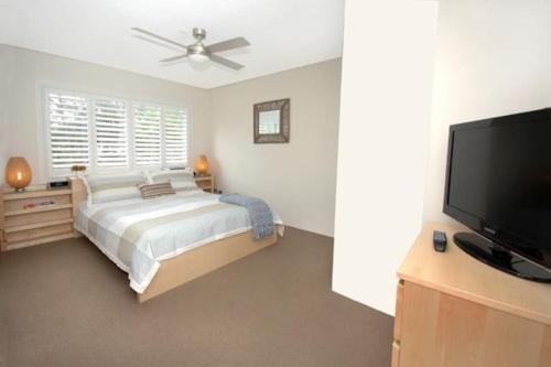 悉尼VELLY-Modern Light 2BR Moments from Clovelly Beach的一间卧室配有一张床和一台平面电视