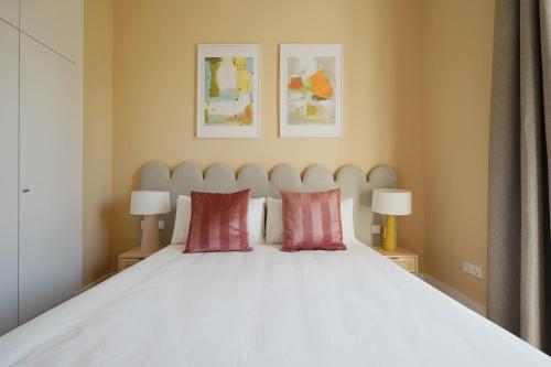 塞维利亚numa I Prestigio Apartments的卧室配有白色床和2个红色枕头