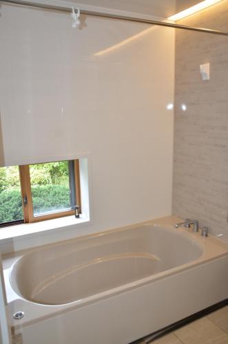 福井Auberge Fujii Fermier的带窗户的浴室内的白色浴缸