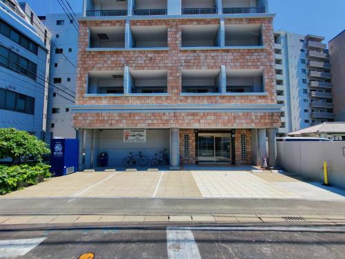 福冈Picolo Hakata的砖楼前的一个空停车位