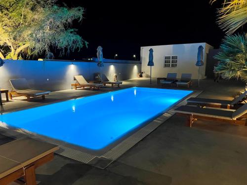 佩里沃罗White Lily Santorini - Adults Only 16 Plus的一座在庭院里放着蓝色灯光的大型游泳池