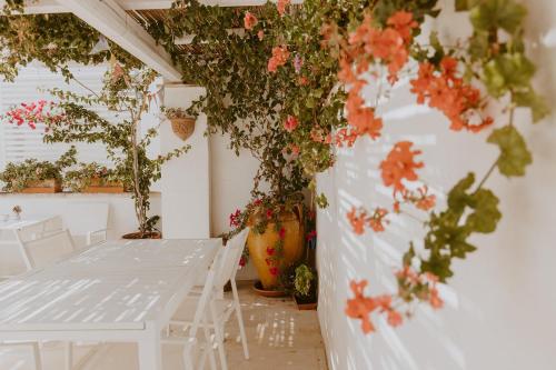 滨海波利尼亚诺Elena's house 30的墙上有白色的桌椅和鲜花