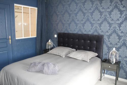 丰特奈勒孔特Althéa, gîte de charme et bien être的一间卧室配有一张带蓝色墙壁的大床