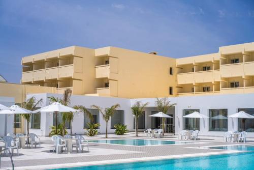 哈马马特达哈亚姆酒店的一个带游泳池、椅子和遮阳伞的酒店