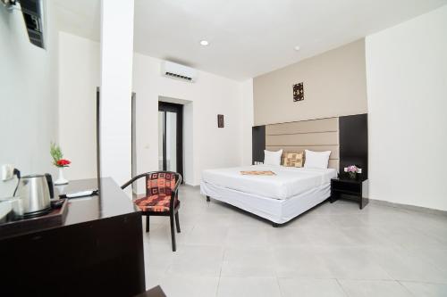 巴马科Dunia Hotel Bamako的卧室配有一张白色大床、一张桌子和椅子