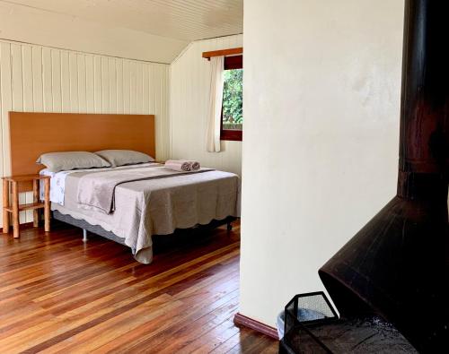 坎巴拉Central Chalés的一间卧室配有一张床,铺有木地板