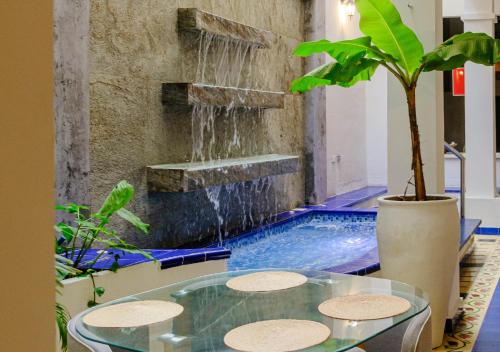 圣玛尔塔Casa Rosa - Alma Hotels的一个带喷泉和玻璃桌的游泳池
