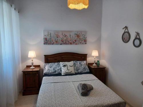 马萨尔福恩Lucky Summer Marsalforn Holiday Apartment的一间卧室配有一张带两个枕头和两个灯的床。