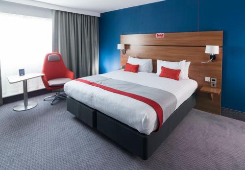 伯明翰伯明翰星城智选假日酒店的酒店客房设有一张大床和一张红色椅子。