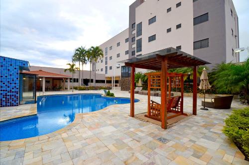 奥托兰迪亚商务公园酒店 的一座游泳池,毗邻一座建筑,设有凉亭