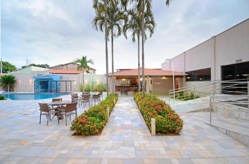 奥托兰迪亚商务公园酒店 的一个带桌椅的庭院,棕榈树