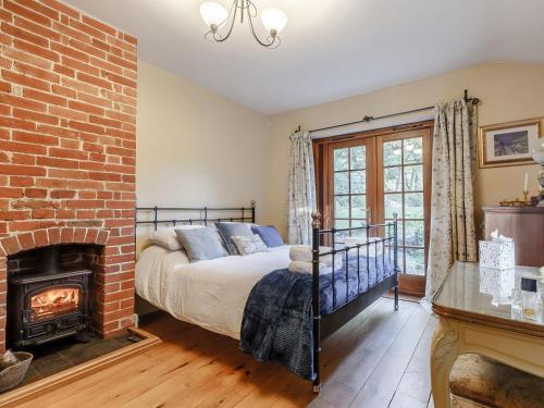 WetheringsettManor Cottage Bungalow的一间卧室配有一张床和一个砖砌壁炉