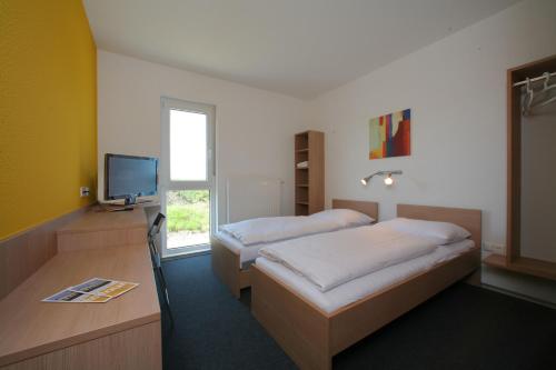 维尔弗斯多夫图尔汽车旅馆的一间卧室设有两张床、一台电视和一扇窗户。