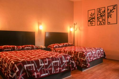 萨卡特卡斯Hotel Alika的橙色墙壁的酒店客房内的两张床