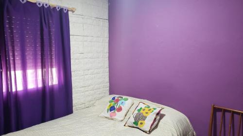 特尔马斯德里奥翁多La casa de valle的一间卧室设有紫色的墙壁和一张带两个枕头的床