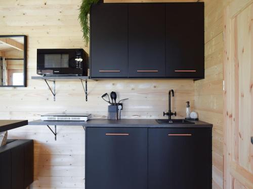 SalinePinewood Cabin的厨房配有黑色橱柜和水槽
