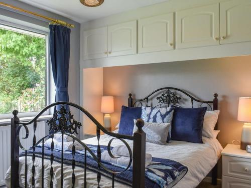 CoundonHaweswater Cottage的一间卧室配有一张带蓝色枕头的床和一扇窗户。