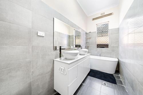 悉尼4 Bedroom house 500M to Drummoyne Bay Run的白色的浴室设有2个盥洗盆和1个浴缸。