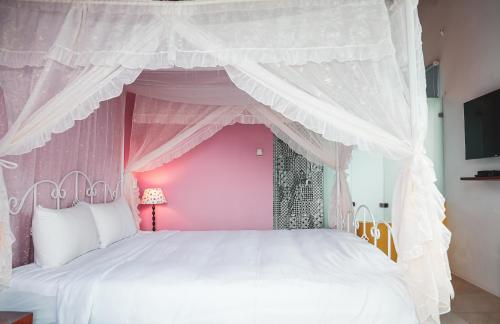 鹅銮鼻垦丁迦南美地-海景花园民宿的粉红色的卧室配有一张带天蓬的白色床