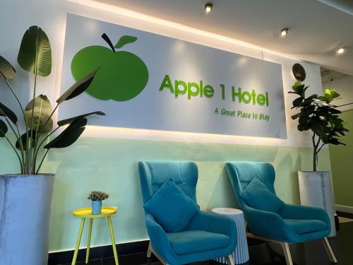 峇六拜Apple 1 Hotel Queensbay的苹果酒店的一个标志,上面有蓝色椅子