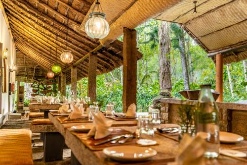提喀迪Amritara Shalimar Spice Garden Resort & Spa的森林里带长桌的餐厅